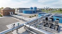 A water treatment facility with stainless steel pipes, flow meters, pumps, and large blue storage tanks.