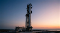 SpaceX Starship rocket stands on its launch pad at sunset near the ocean.