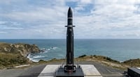 A Rocket Lab Electron rocket stands on a launch pad overlooking a coastal cliffside.