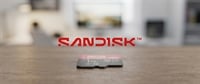 SanDisk logo above a 1TB Extreme Pro microSD memory card resting on a wooden table.