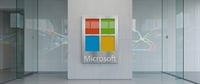 Microsoft logo displayed on a wall-mounted plaque in a modern office lobby with glass partitions.