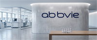 AbbVie logo on a curved wall in an office lobby, with a laboratory and vials visible nearby.