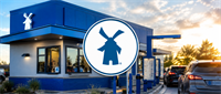 Dutch Bros drive-thru location with windmill logo signage and cars in line at dusk.