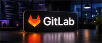 Illuminated GitLab logo sign on a desk in a dimly lit office with a computer screen and plant.