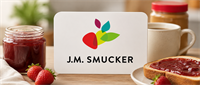 J.M. Smucker logo card on a table with jam, peanut butter, coffee, strawberries, and toast.