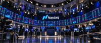 Nasdaq logo displayed beneath curved digital screens showing stock market data in the Nasdaq MarketSite studio.