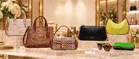 Coach and Kate Spade handbags, sunglasses, and accessories displayed on a store showcase.