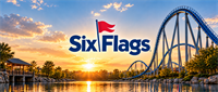Six Flags logo displayed over a roller coaster and lake at sunset in an amusement park setting.