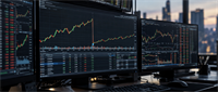 Multi-monitor trading desk displaying candlestick stock price charts, market data tables, and a city skyline at dusk.