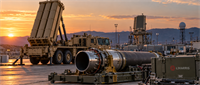 Military missile launcher and radar equipment at sunset with L3Harris branded container in foreground.