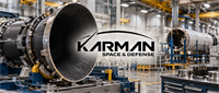 Karman Space & Defense logo overlaid on a factory floor with large cylindrical aerospace components in production.